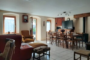 Ein geräumiges Wohnzimmer mit einem roten Sofa, einem Holzesstisch und einem Fernseher.
