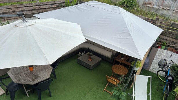 Un espace extérieur abrité, aménagé avec une table et des chaises, un canapé et un vélo.