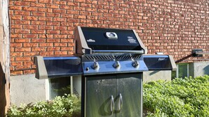 Een barbecue met een digitaal display, voor een bakstenen muur.