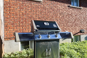 Una parrilla para barbacoa con pantalla digital, frente a un muro de ladrillo.