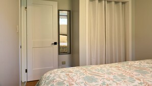 Een slaapkamer met een bed, een deur en een inloopkast met spiegel.