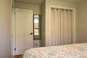 A bedroom with a bed, a door, and a closet with a mirror.
