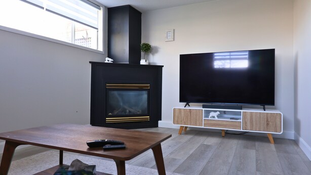 Een woonkamer met een open haard, een tv op een houten standaard en een tafel met een afstandsbediening.
