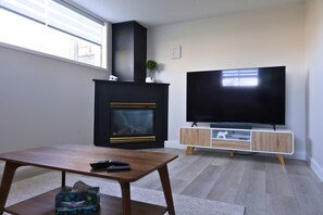 A living room with a fireplace, a TV on a wooden stand, and a table with a remote control.