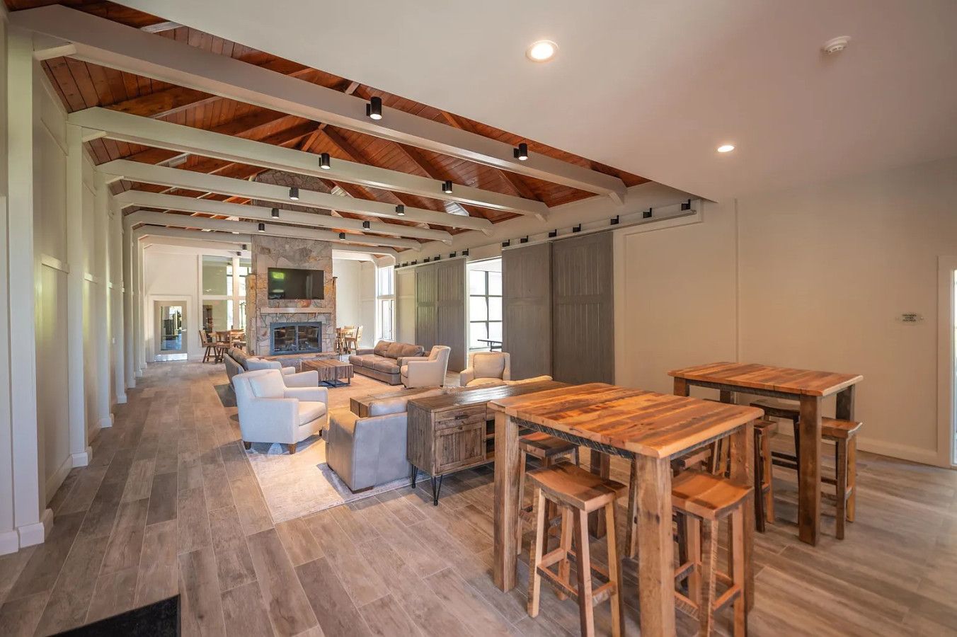 A spacious living area with a fireplace, sofas, and a wooden dining table.