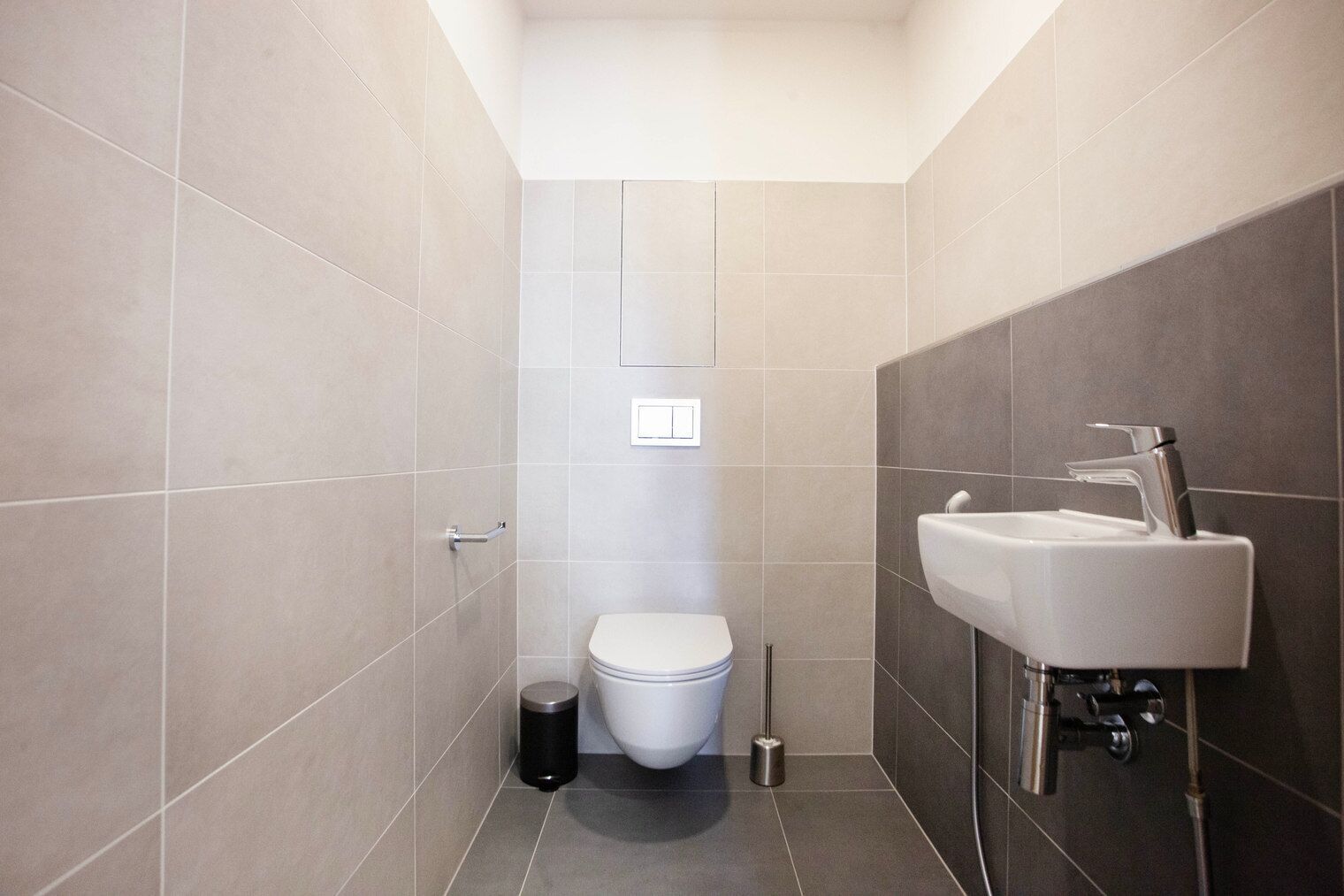 Une salle de bain moderne équipée de toilettes, d’un lavabo et d’une barre d’appui.