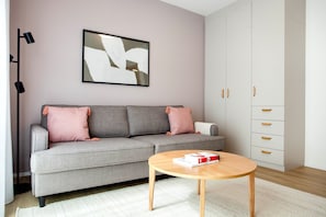 A modern living room with a grey sofa, a round wooden coffee table, and a white wardrobe with multiple drawers. - Blueground Holešovice, Family-friendly, nr Park (Prague)