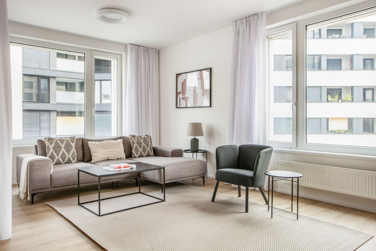 A modern living room with a sofa, armchair, coffee table, and a small side table.