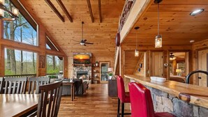 A wooden interior with a dining area, bar, and stone fireplace. - Grounding Lodge | Sauna + Cold Plunge + Hot Tub (Blue Ridge)