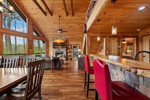 Ein Holzinnenraum mit Essbereich, Bar und Kamin aus Stein.