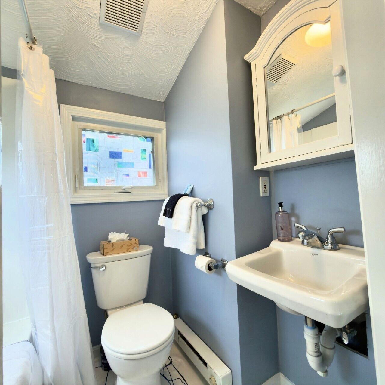 A bathroom with a toilet, sink, and window.