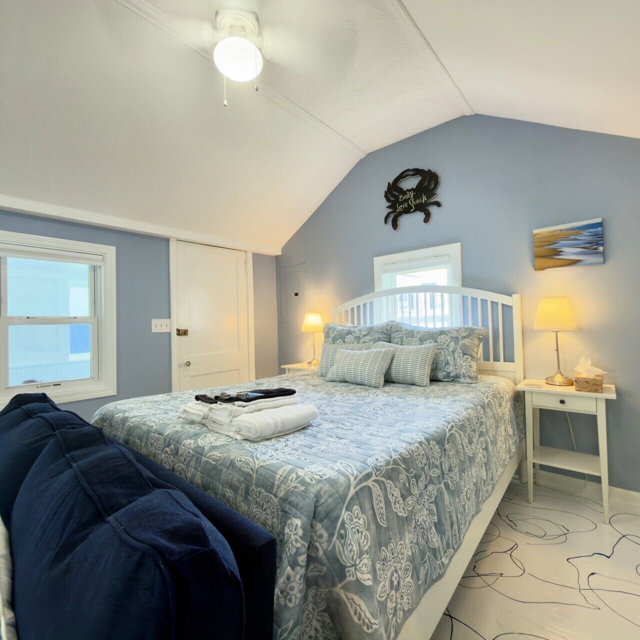 Een slaapkamer met een bed, nachtkastjes, een wandklok en een raam.