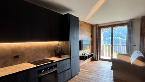 Une cuisine moderne avec des meubles de couleur sombre, un plan de travail en bois et un four encastré.