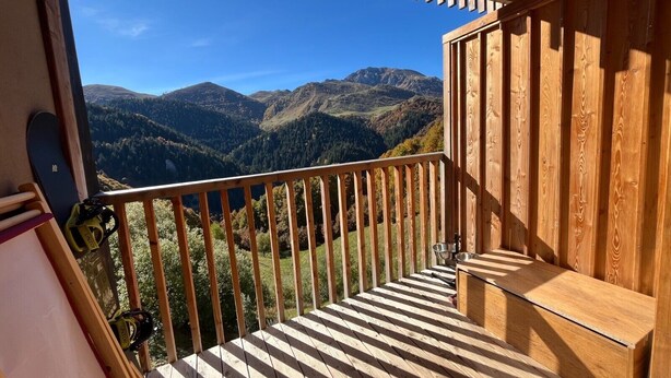 Un balcon en bois offrant une vue sur les montagnes.