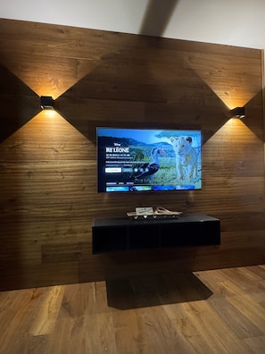 Ein Flachbildfernseher an einer Holzwand, darunter ein Holzboden.