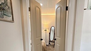 Un pasillo con dos puertas abiertas que dan a una habitación con cama y espejo.