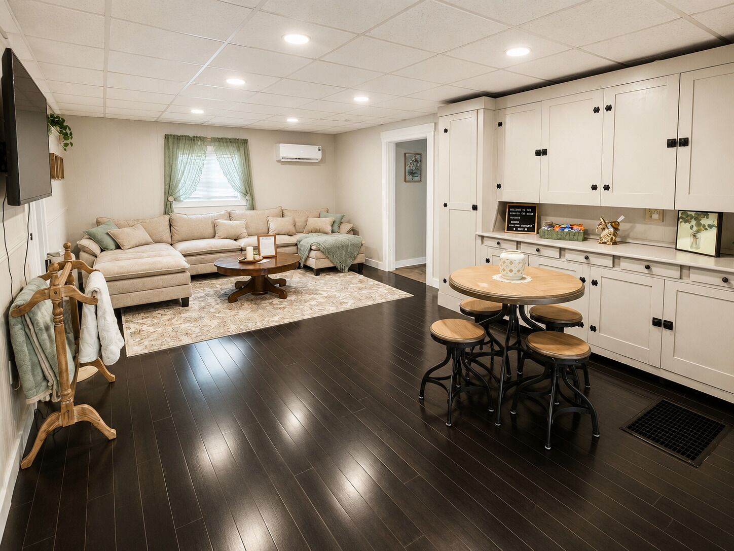 A modern living room with a sofa, coffee table, and a dining area with stools.
