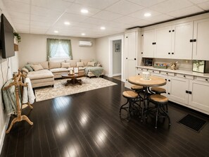 Una sala moderna con un sofá, una mesa de centro y un comedor con taburetes.