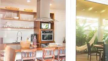Una cocina con televisor, horno y barra con sillas.