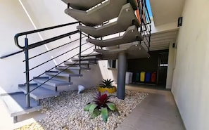 A modern staircase with metal railings, a gravel pathway, and a potted plant. - Cozy Suite for Couples (SC)