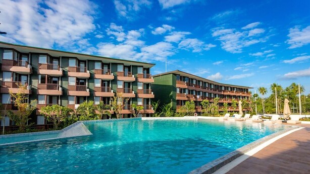 Un hôtel doté d’une piscine, de plusieurs balcons et d’un jardin tropical.