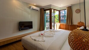 Une chambre d’hôtel équipée d’un lit, d’une télévision, d’un climatiseur, d’une fenêtre avec des rideaux et d’une lampe décorative.