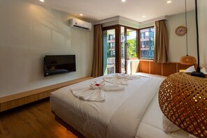 Ein Hotelzimmer mit Bett, Fernseher, Klimaanlage, einem Fenster mit Vorhängen und einer dekorativen Lampe.