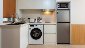 Une cuisine compacte équipée d’un lave-linge, d’un four à micro-ondes et d’un réfrigérateur.