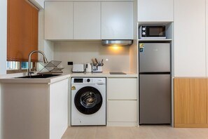 Eine kleine Küche mit Waschmaschine, Mikrowelle und Kühlschrank.