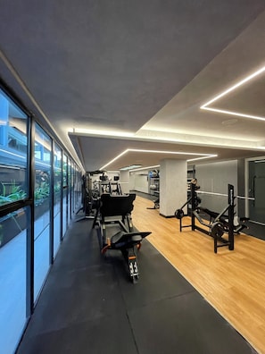 A modern gym with exercise equipment, large windows, and a wooden floor. - Luxury Apartment in HIT Cabo Branco (João Pessoa)