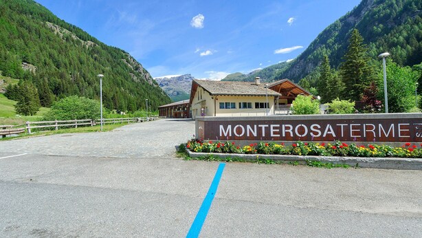 A building with a sign reading 'MONTEROSATERME' in front of a mountainous landscape. - Holiday Home 'Lueur De La Rouja' with Mountain View (Champoluc)