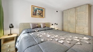 A bedroom with a bed, a nightstand, a lamp, a wardrobe, and a painting on the wall. - Holiday Home 'Lueur De La Rouja' with Mountain View (Champoluc)