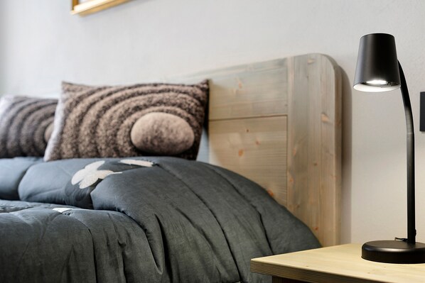 A bed with a headboard, a bedside table, and a lamp.