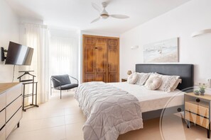 Ein Schlafzimmer mit Bett, Fernseher, Sessel, Kleiderschrank und einem Bild an der Wand.