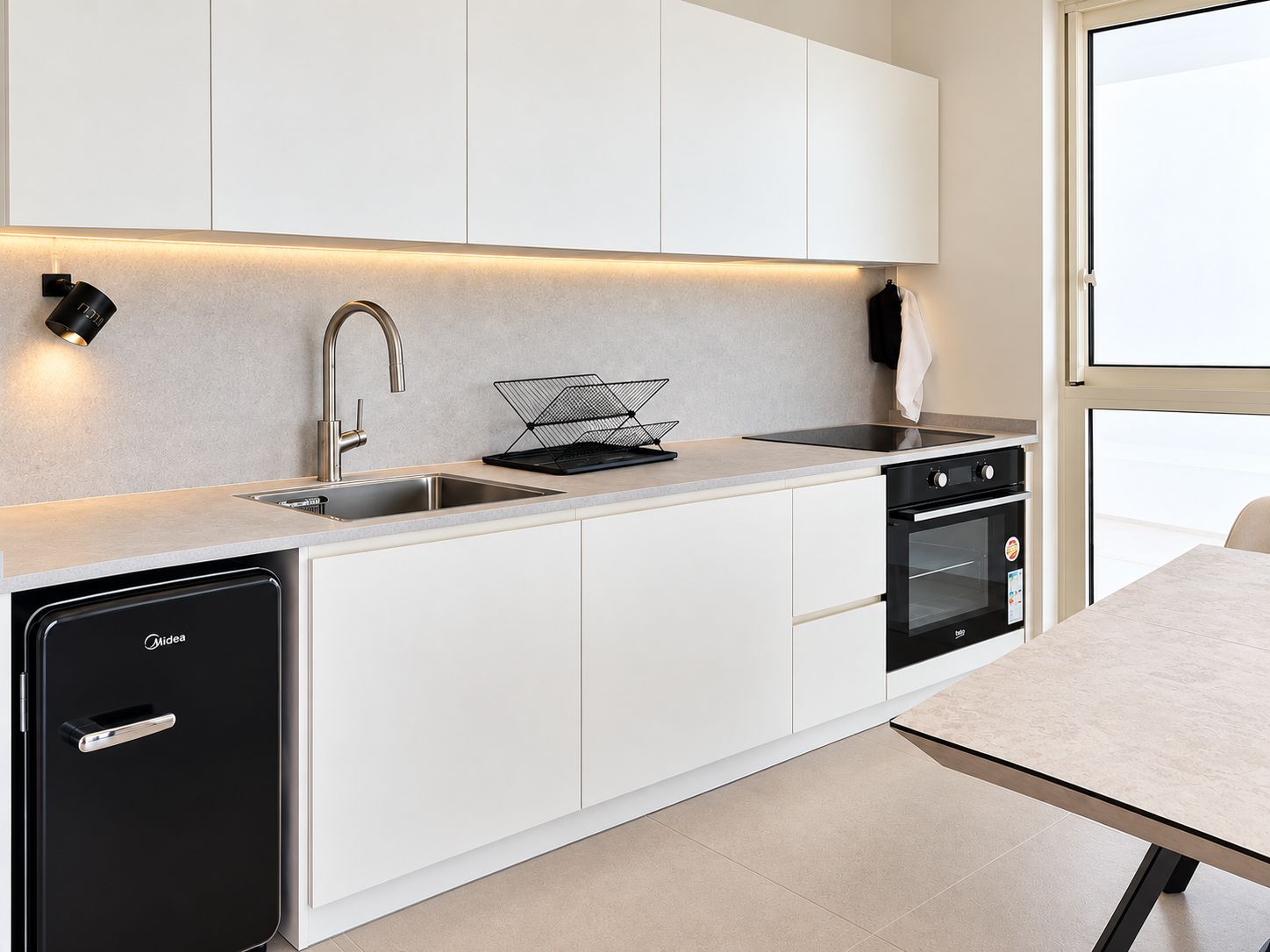 Une cuisine moderne avec des meubles blancs, un lave-vaisselle noir, une cuisinière et un évier.