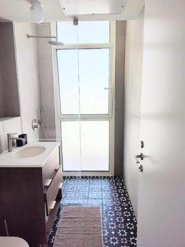 Un baño con un ventanal grande, un lavabo y una ducha.