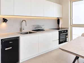 A modern kitchen with white cabinets, a black dishwasher, a stove, and a sink. - Ocean's Edge Suite at 42 Eilat (Eilat)