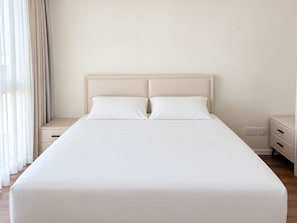 A neatly made bed with a headboard, two bedside tables, and a window with sheer curtains. - Ocean's Edge Suite at 42 Eilat (Eilat)