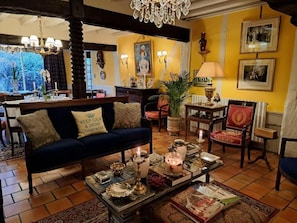 A cozy living room with a sofa, chairs, a coffee table with candles, and a chandelier.