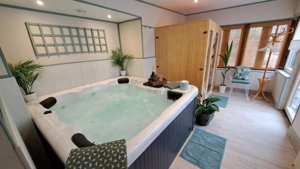 A spa room with a hot tub, wooden cabinets, a chair, and potted plants.