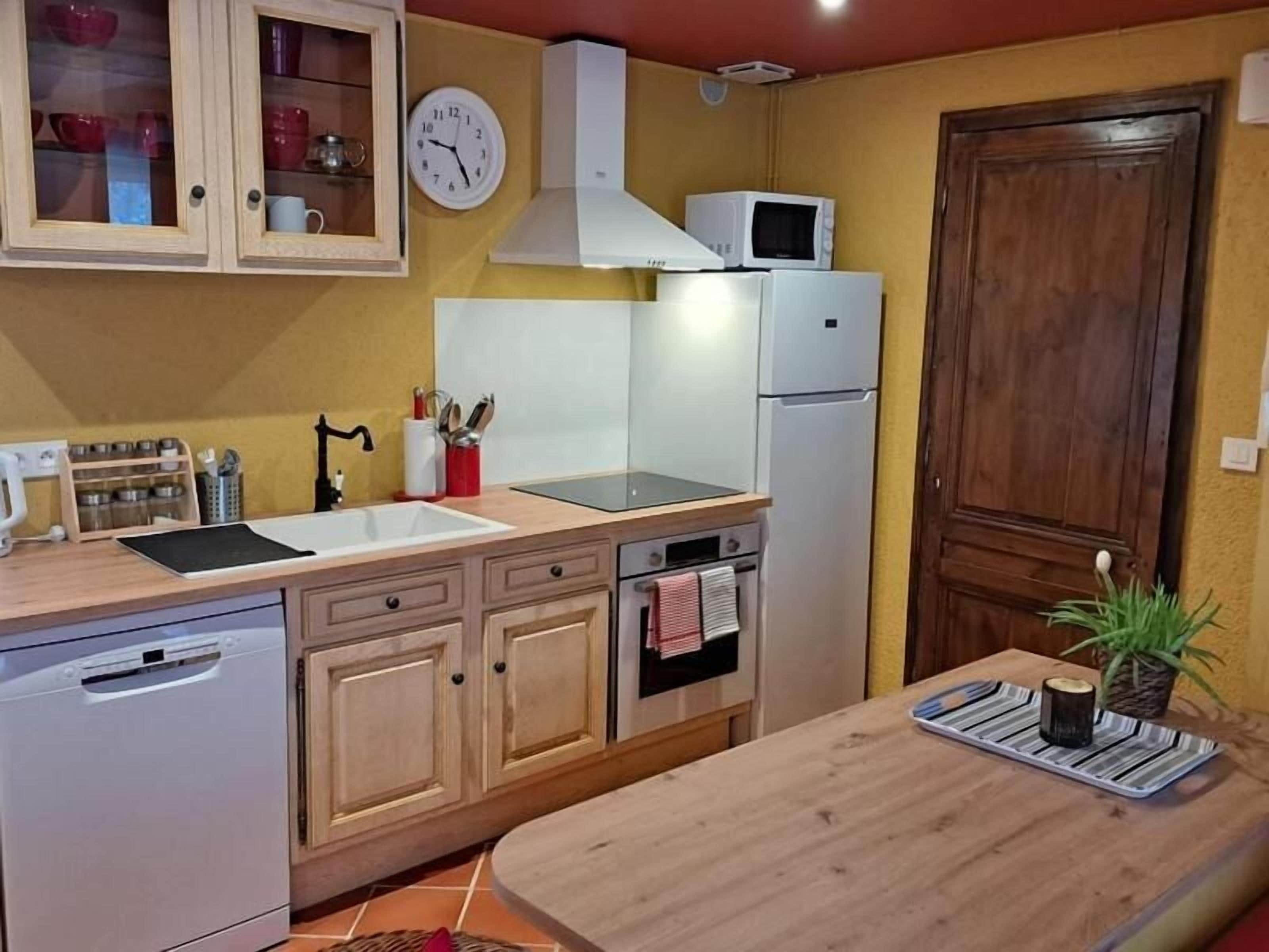 Cocina compacta con microondas, horno, lavaplatos y armarios de madera.