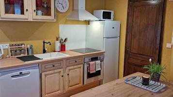 Cocina compacta con microondas, horno, lavaplatos y armarios de madera.