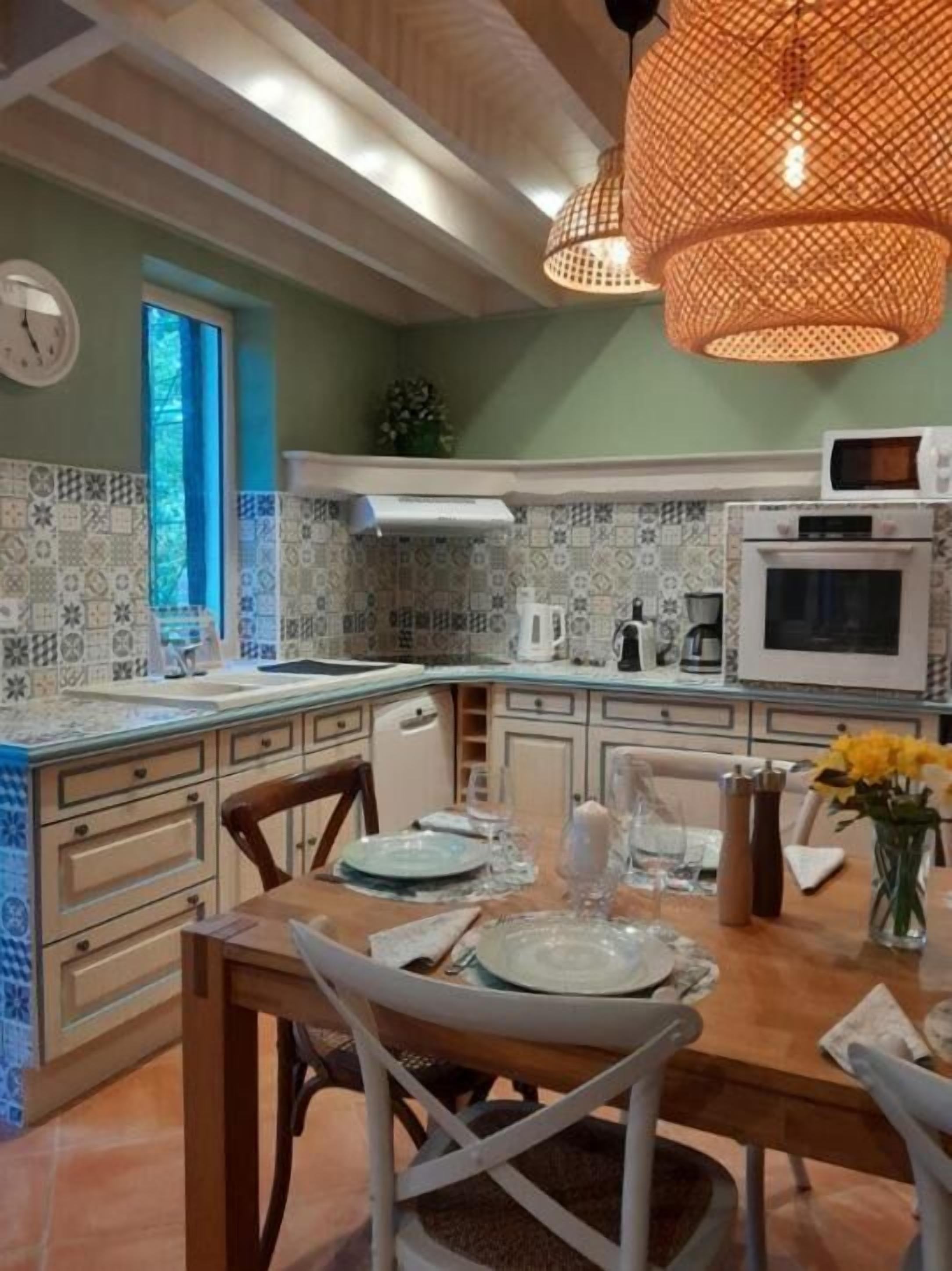Una cocina con baldosas estampadas, una mesa de comedor lista y una lámpara colgante.