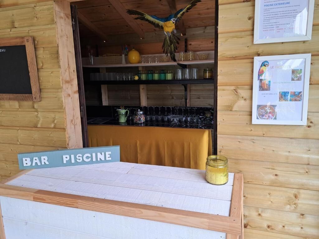 A wooden bar area with a sign reading 'BAR PISCINE,' shelves with glassware, and a framed menu.