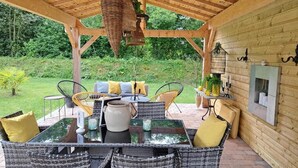 An outdoor patio with wicker furniture, a hanging basket, and a brick floor.