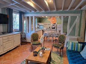A living room with a sofa, chairs, a coffee table, and a kitchen area with a dining table and chairs.