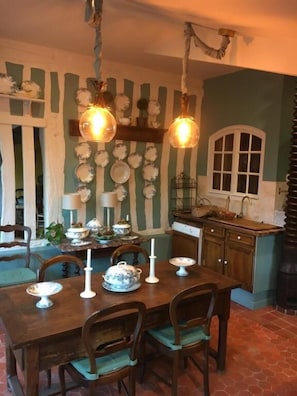 A dining area with a wooden table, chairs, and hanging light fixtures.