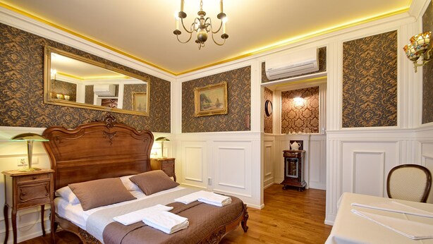 Une chambre à coucher avec un lit en bois, une table de chevet, une table, une chaise, un lustre et un miroir.