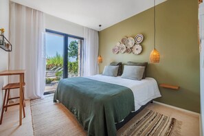 Quarto com cama, escrivaninha, vista para o exterior e arte decorativa na parede.
