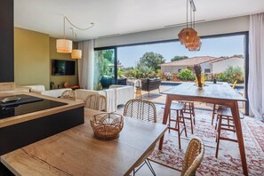 Eine moderne Küche mit Essbereich, großen Fenstern und Blick auf den Garten.
